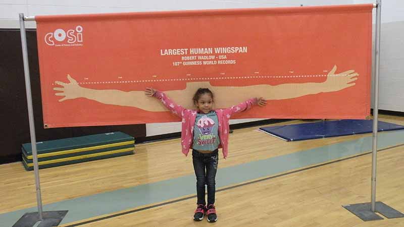 A student compares her arm span to that of the largest in the world.