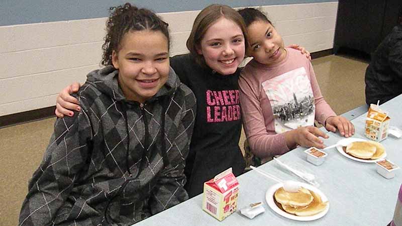 Students pause for a photo while enjoying their pancakes.