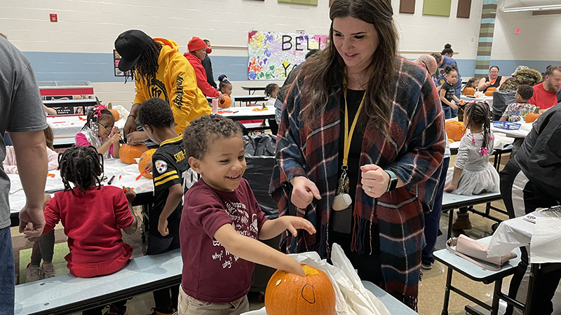 Ms. Komsa helps a student with his pumpkin.